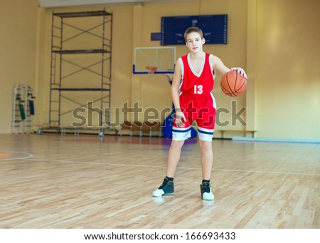 Basketball player with a ball in his hands and a red uniform.  Basketball player practicing in the gym