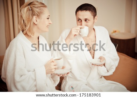 Man and woman drinking coffee in the morning in bed. Young lovers lay in bed