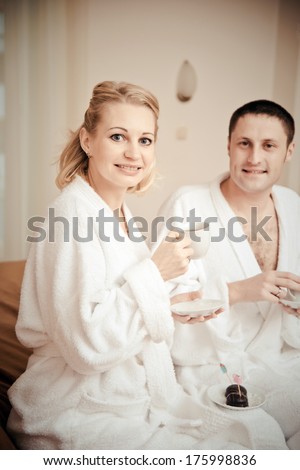Man and woman drinking coffee in the morning in bed. Young lovers lay in bed. man and woman eat cake in bed