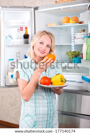 Young beautiful girl takes food from the refrigerator. Storing food in the refrigerator
