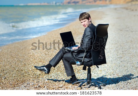 Freelancer working at a laptop. A man working on a computer at the seaside