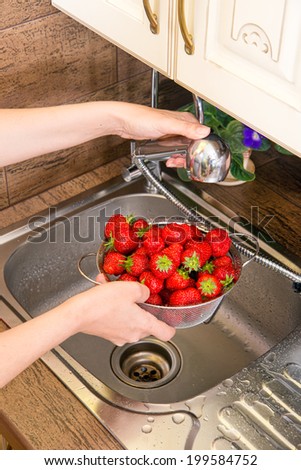 washes strawberries in the kitchen