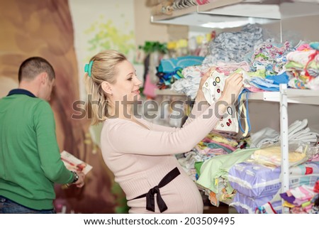 Young happy family in the store buying clothes for a newborn