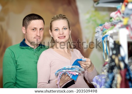 Young happy family in the store buying clothes for a newborn