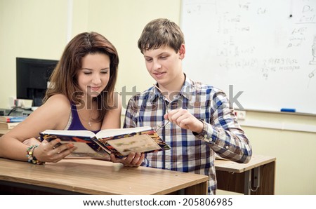 happy beautiful student reading a book in a classroom