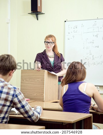 Cheerful teacher with students posing in front of blackboard