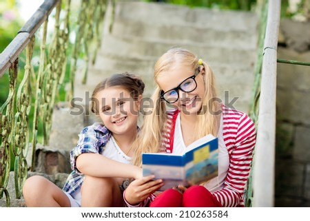 Children reading a book in the park outdoors