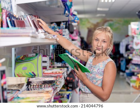 Schoolgirl buys exercise book Office goods in store for school. Buying school supplies at the supermarket