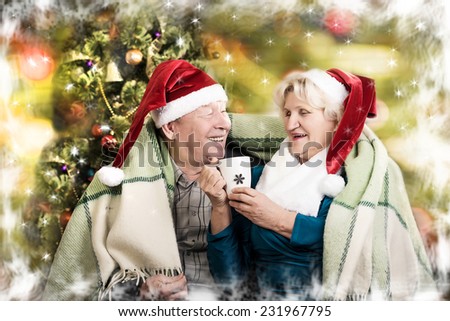 Happy beautiful elderly couple celebrating new family, holidays, christmas, age and people concept - happy senior couple in santa helper hats sitting on sofa over living room