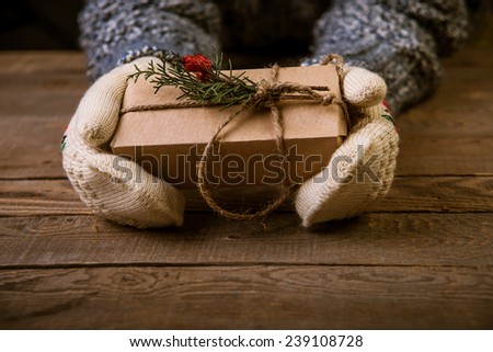 Hands in mittens holding gift box. Woman holding modern Christmas present gift
