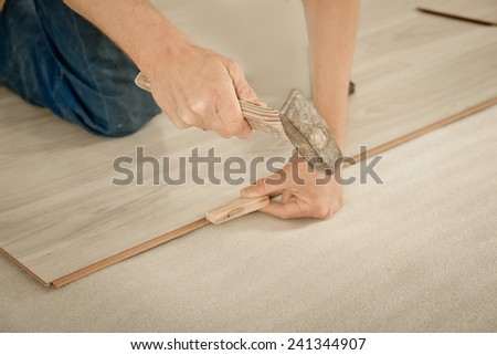 Installing laminate flooring fitting the next piece - focus on hand. Man laying laminate flooring