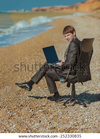 man with laptop sitting in an office chair outdoors
