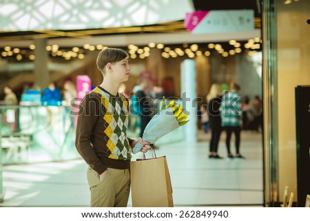 young man with shopping bags, man in shop with bags and a bouquet of tulips