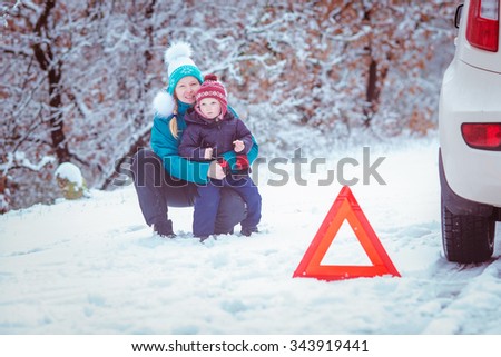 Winter road, emergency warning triangle, a woman with a child in a road accident