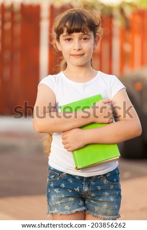Cute Little School Girl hugs a Book