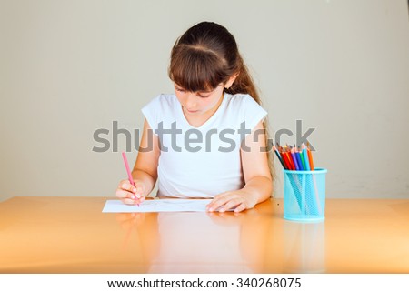 Cute little girl with red sketch pen is drawing at kindergarten