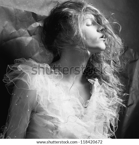 Retro portrait of a dreaming queen like girl over wrinkled black paper background. black and white studio shot