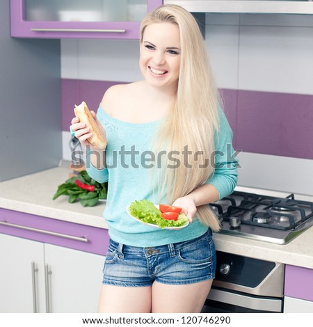 Lovely young pregnant woman enjoying fresh bread and salad  in her modern kitchen. indoor shot