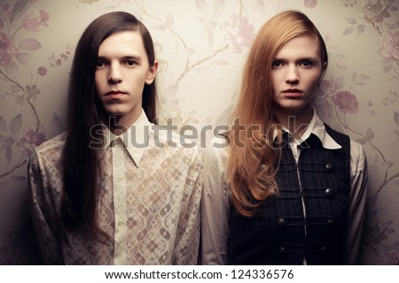 Portrait Of Beautiful Long Haired People In Vintage Style: Handsome Boy With Brown Hair And Gorgeous Red-Haired Girl Posing Together. Studio Shot.