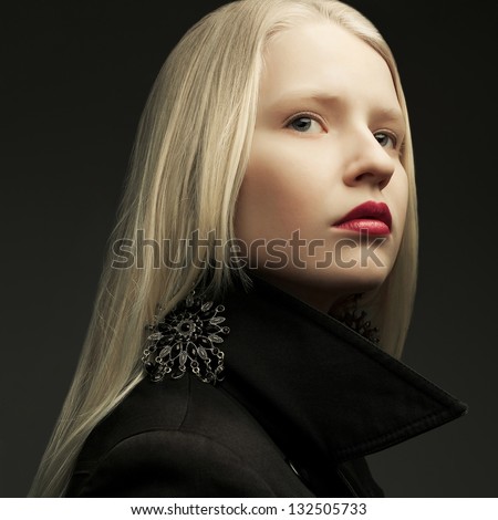 Portrait of a beautiful fashionable model with natural blond hair and great make-up posing over dark gray background. Close up. Studio shot