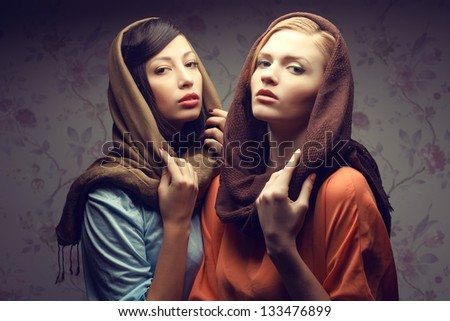 Portrait of two gorgeous young women (brunette and red-haired) in shawls and vintage dresses. Retro (classic, hollywood) style. Perfect hair, skin and make-up. Studio shot