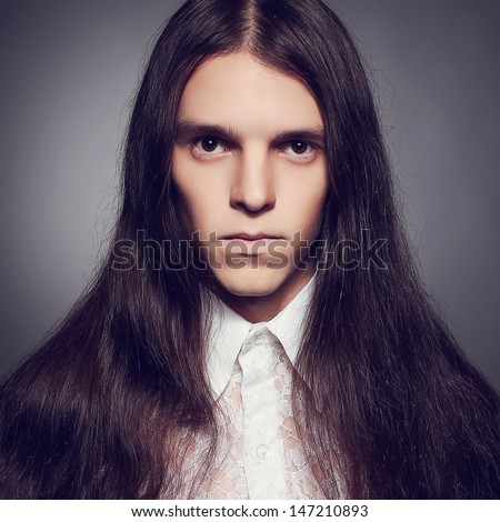 Old fashioned portrait of a long-haired young man in white vintage shirt posing over dark gray background. Retro (classic) style. Close up. Studio shot
