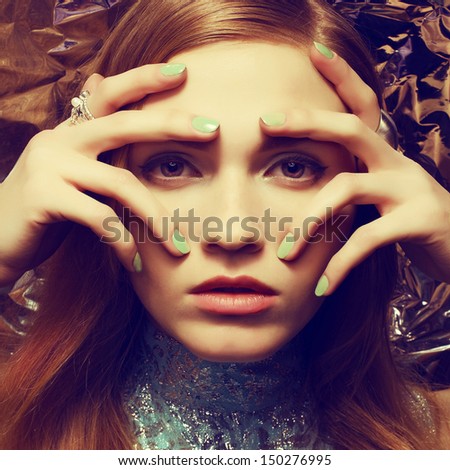 Vintage portrait of beautiful woman with long healthy shiny red (ginger) hair, perfect makeup and stylish silver accessories on her hands. Hands on face. Close up. Retro-futurism style