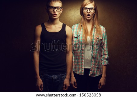 Portrait of gorgeous red-haired (ginger) fashion twins in casual shirts wearing trendy glasses, posing over golden background together with wow faces (duck-face). Hipster style. Copyspace. Studio shot