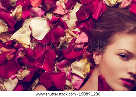 Vintage Spa Concept. Portrait Of A Fashionable Red-Haired (Ginger) Model With Sexy Pink Lips Lying On Fading Rose Petals Background. Retro Style. Close Up. Copy-Space. Studio Shot