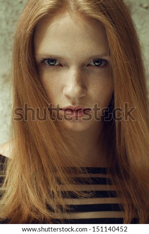 Portrait of a beautiful red-haired (ginger) model with freckles on her face. Healthy long hair. Daylight. Close up. Outdoor shot