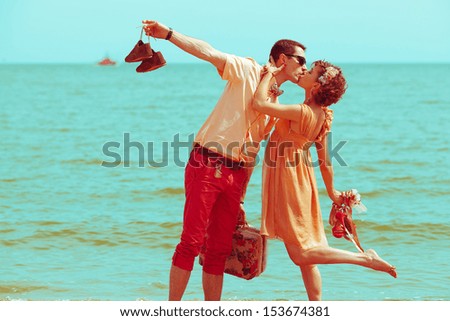 Couple walking on beach Young happy married hipsters in trendy clothes kissing on beach and holding their shoes Sunny summer day Copy-space Outdoor shot Couple walking on beach Young happy married hipsters in trendy clothes kissing on beach and holding their shoes Sunny summer day Copy-space Outdoor shot