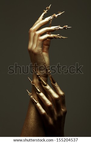 Art Manicure Concept. Beautiful Golden Hands With Golden Long Arty Nails. Close Up. Studio Shot