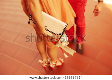The First Date Concept. Young Couple Of Hipsters Wearing Trendy Clothing And Shoes Standing Together On Stairs. Sunny Day. Copy-Space. Outdoor Shot
