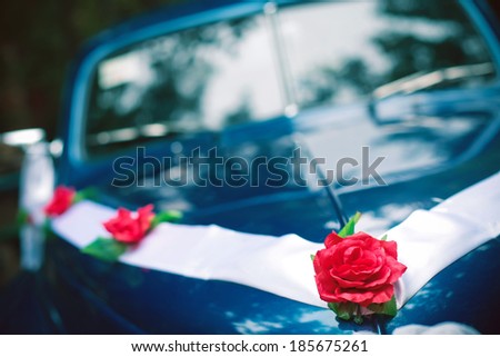 Blue colored vintage wedding car decorated with roses and white ribbon. Hipster style. Daylight. Close up. Copy-space. Outdoor shot