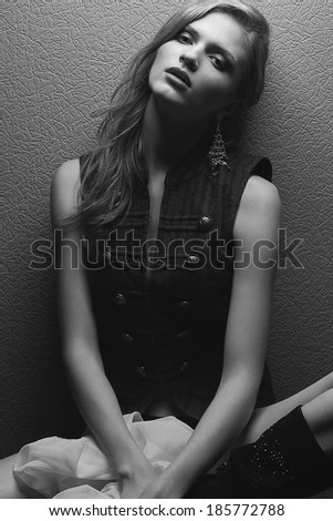 Emotive portrait of a beautiful fashion model posing over gray background. Black and white (monochrome) studio photo