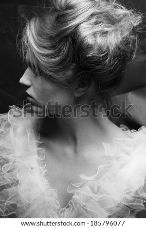 Vintage profile portrait of a crazy queen like girl posing over wrinkled black paper background. Retro style. Black and white (monochrome) studio shot