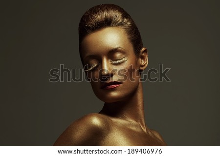 Creative make-up concept. Portrait of a sleeping beauty with perfect golden skin and hair. Bright long golden lashes, long neck and gorgeous cherry lips. Close up. Studio fashion shot