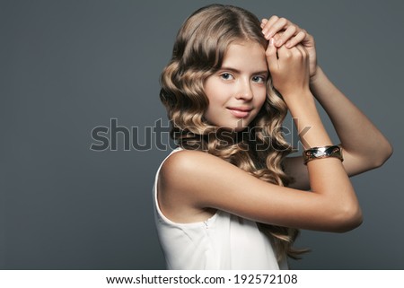 Perfect hair concept. Emotive portrait of a beautiful teen girl with healthy long glossy hair and luxurious golden armlet. Hands near head. Close up. Copy-space. Vintage style. Studio shot