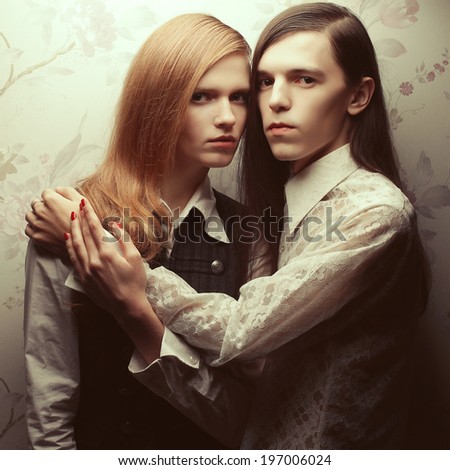 Gothic hipsters concept. Portrait of beautiful long haired people in vintage style: handsome guy with brown hair and gorgeous red-haired girl posing together. Studio shot