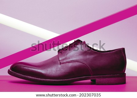 Brown leather men\'s shoes with violet neon light lamp over lavender and violet background. Vogue style. Art fashion studio shot