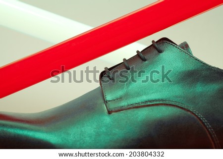 Stylish and arty hipster footwear fashion concept in disco style. Trendy leather men\'s shoes with red and white neon light lamps over gray background. Close up. Studio shot