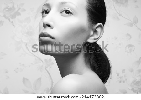 Vintage portrait of glamorous retro girl posing over vintage wall. Hollywood style (film noir). Perfect skin and hairdo. Natural make-up. Close up. Black and white (monochrome) studio shot