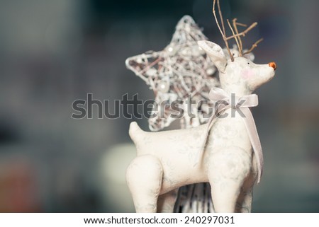 Christmas decoration concept. Vintage toy - christmas deer - with bow on its neck standing over white christmas star. Pastel colors. Retro style. Close up. Indoor shot