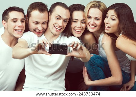 Best moments concept. Group of happy smiling and laughing friends in casual clothing taking selfie with smartphone. Urban street style. Studio shot