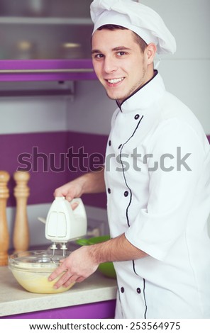 Dessert cooking concept. Portrait of smiling male chef cooking food and standing in the modern kitchen of restaurant. Indoor shot