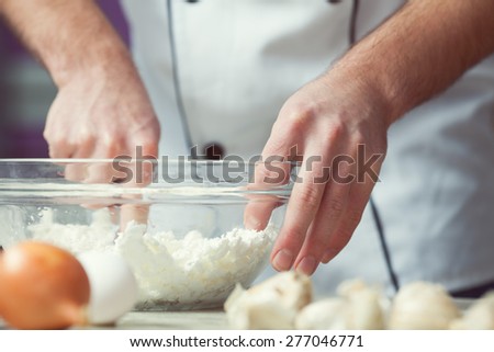 Vegetarian bakery concept. Chef\'s hands mixing feta cheese and eggs in kitchen of cafe, restaurant. Close up. Indoor shot