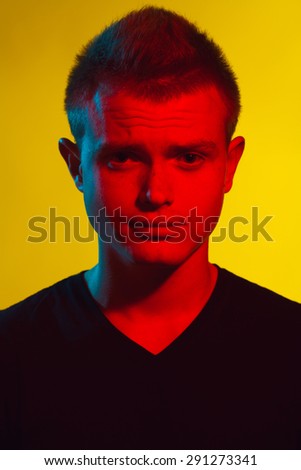 Pop-art style concept. Portrait of brutal young man with short hair wearing black t-shirt and posing over yellow background. Hipster style. Close up. Studio shot