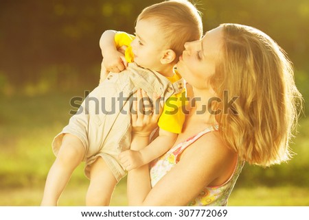 Happy family, friends forever concept. Profile portrait of smiling mother and little son playing together in park. Mom holding baby. Sunny summer day. Close up. Copy-space. Outdoor shot