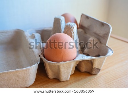 Eggs in paper tray on wooden background