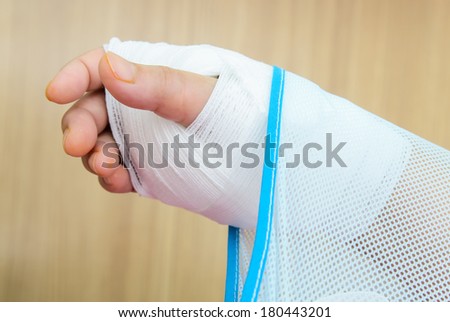 Hand injury with white medicine bandage wearing hand sling